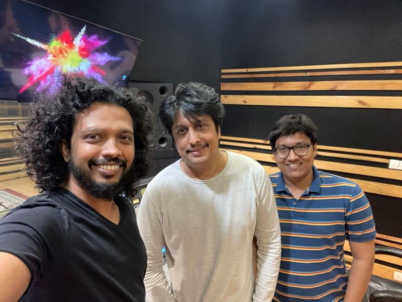 Three collaborators smiling in a recording studio