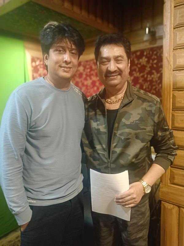 Aslam Keyi with a singer holding lyric sheets in a recording room