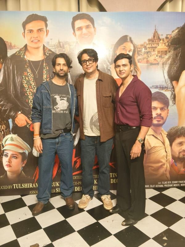Cast and crew in front of a film poster